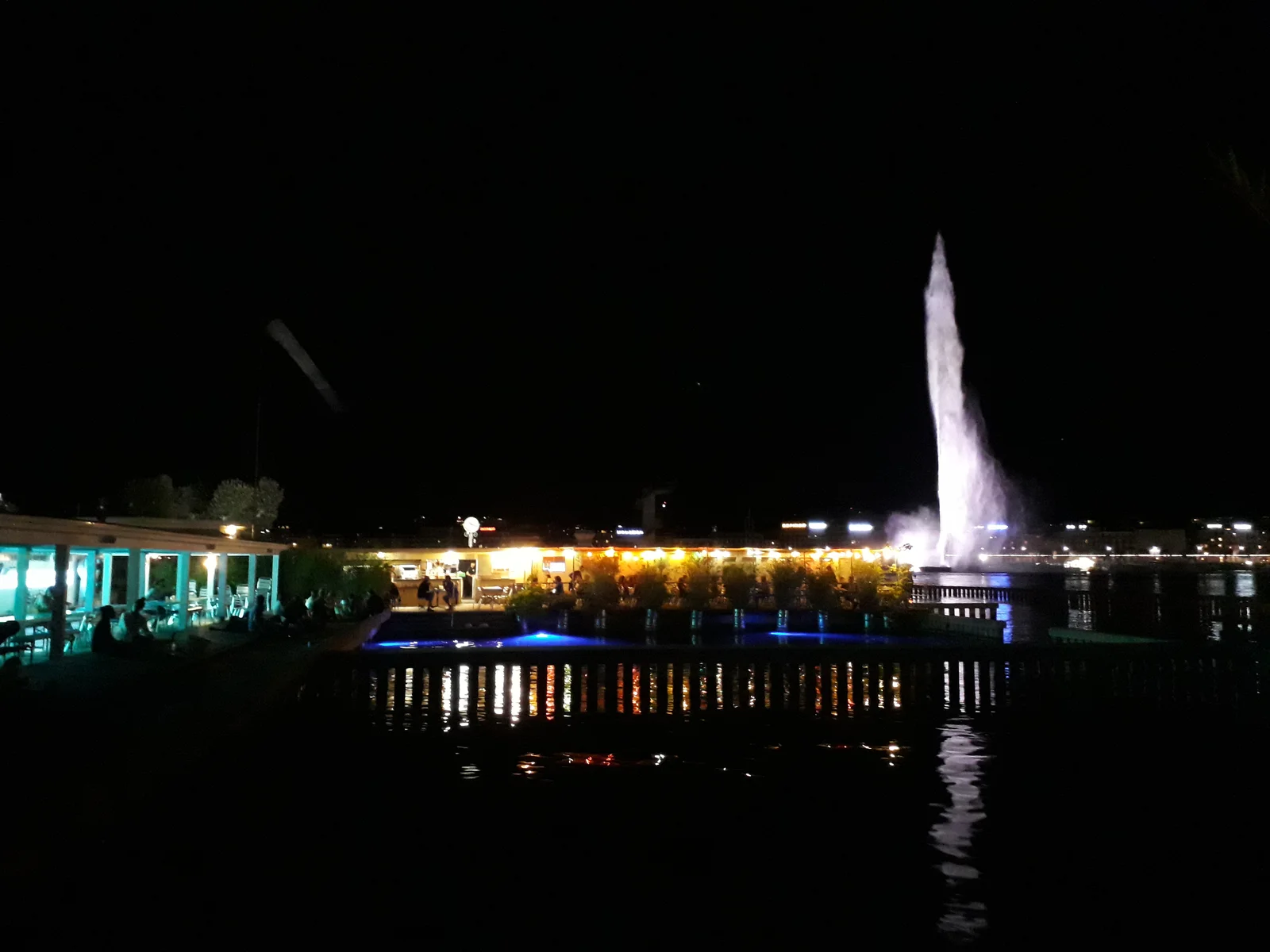 Buvette des Bains des Pâquis à Genève, terrasse le soir avec le Jet d'eau en arrière-plan