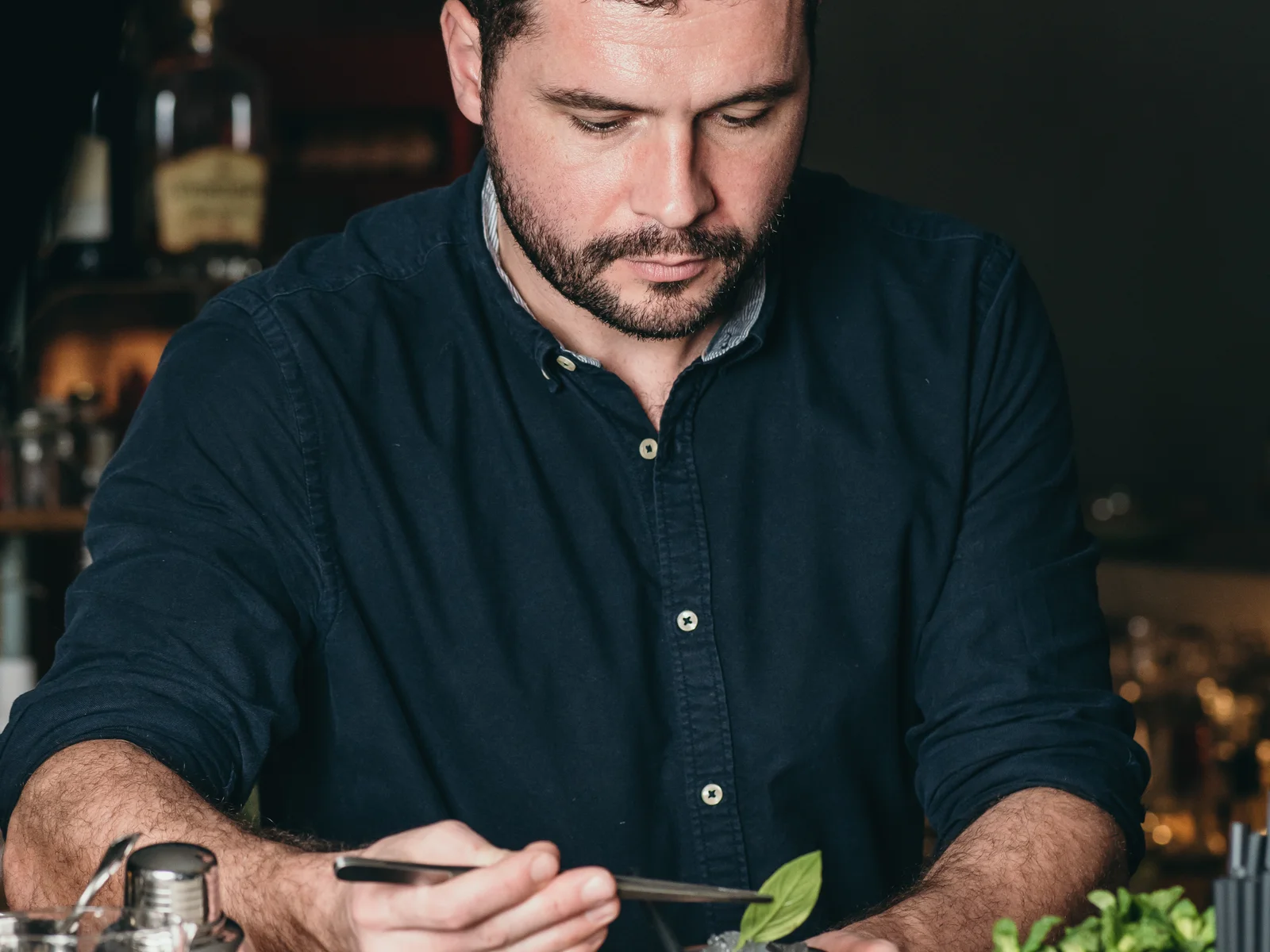 Le Verre à Monique à Genève, un barman prépare un cocktail au comptoir