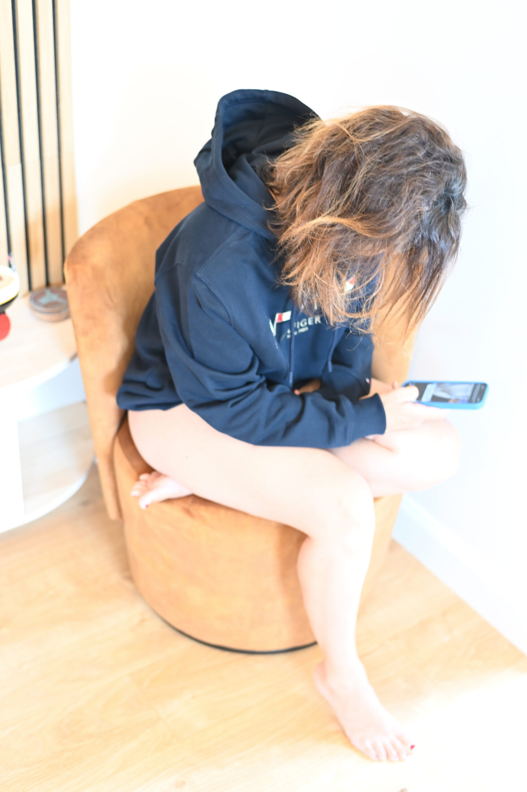 Léna en sweat à capuche Tommy Hilfiger sur un fauteuil blanc