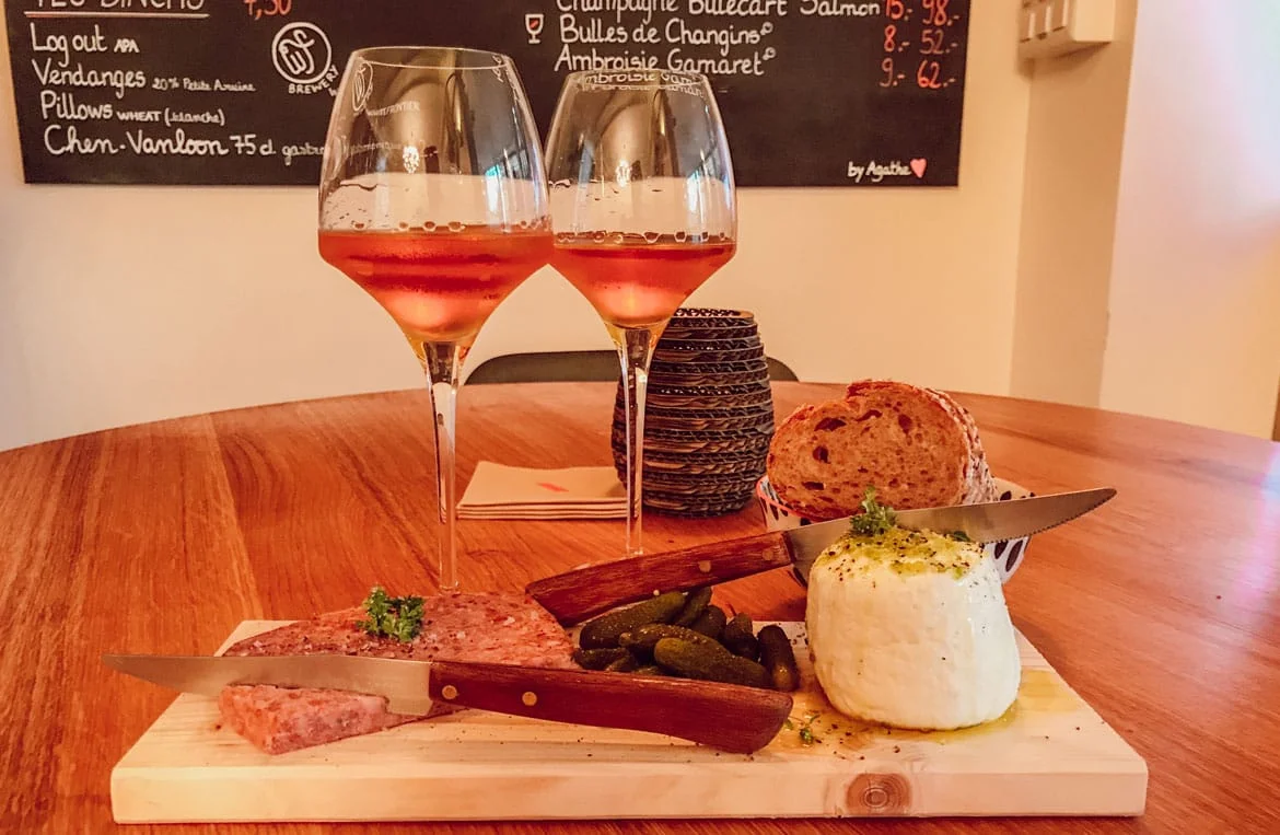 Planchette et verres de vin sur une table de Ta Cave à Lausanne